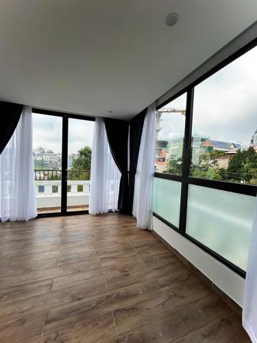 Una habitación con ventanas de piso a techo y pisos de madera. en Memory Inn - Green Villa, en Da Lat