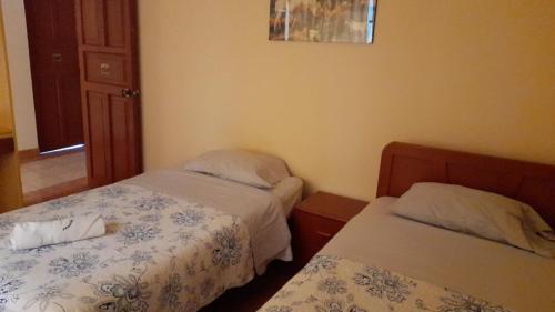 1 dormitorio con 2 camas, ventana y puerta en Hotel Aquarius, en Chimbote