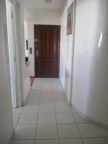 a hallway with a brown door and a white tile floor at Abokhalid in Agadir