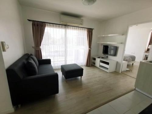 a living room with a black couch and a television at Luxury 2 bedrooms condo in Kho Takiab in Hua Hin
