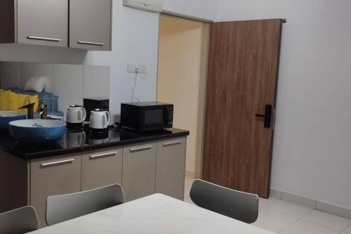 a kitchen with a table and a tv on a counter at HMM Lili - Nilai in Nilai