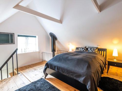 a bedroom with a bed with a black comforter and a window at Holiday home Vejers Strand XIX in Vejers Strand