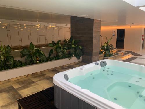 a large bath tub in a bathroom with plants at Espectacular departamento con vista a la Carolina con Generador de luz in Quito