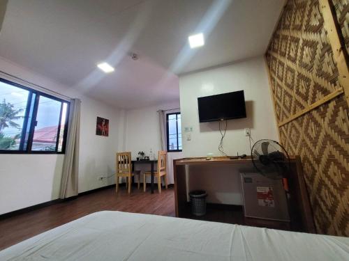a bedroom with a bed and a desk with a television at Gaja Go Dive & Inn in Moalboal