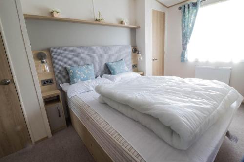 Schlafzimmer mit einem großen weißen Bett und einem Fenster in der Unterkunft Beautiful 6 Berth Caravan With Full Sea Views For Hire In Suffolk Ref 68002cr in Lowestoft