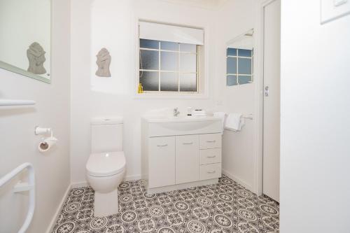 a white bathroom with a toilet and a sink at Relax on Rata, Cottage 1 in Twizel