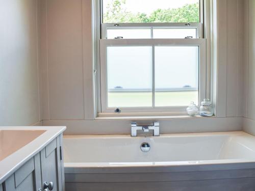 a bathroom with a bath tub and a window at Forge Cottage in Bradenham
