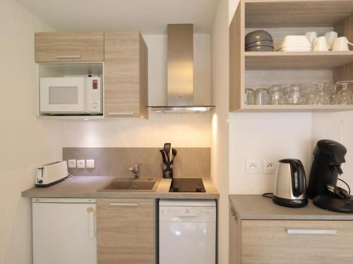 une petite cuisine avec un évier et un micro-ondes dans l'établissement Appartement Centre Les Gets - Balcon, 6 Couchages, Proche Remontées, Animaux Acceptés - FR-1-623-217, aux Gets