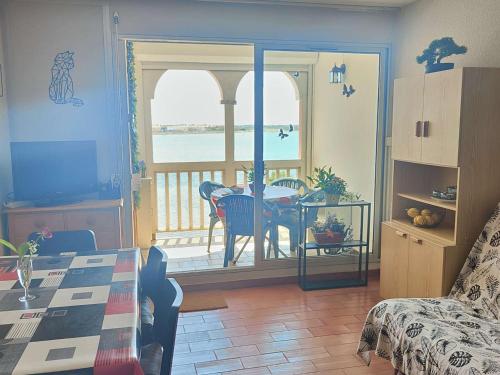 d'un salon avec une table et un balcon. dans l'établissement Appartement T2 Cabine 6 pers avec Piscine - Le Barcarès - FR-1-195-100, au Barcarès