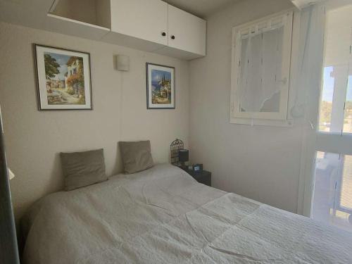 une chambre blanche avec un lit et une fenêtre dans l'établissement Appartement T2 Cabine 6 pers avec Piscine - Le Barcarès - FR-1-195-100, au Barcarès