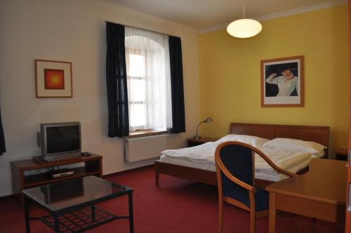 1 dormitorio con cama, mesa y TV en Penzion u Coufalů en Loštice