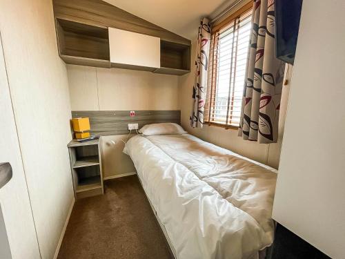 a small bedroom with a bed and a window at Lovely Caravan With Decking Free Wifi At North Denes Caravan Park Ref 40145nd in Lowestoft