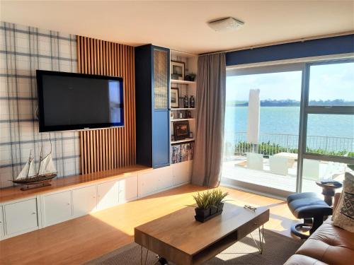 - un salon avec une télévision et une vue sur l'océan dans l'établissement Once Upon a Tide, à Auckland