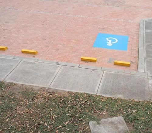 a blue sign on the side of a sidewalk with a handicap sign at PeñalisaKapoSalSar in Girardot
