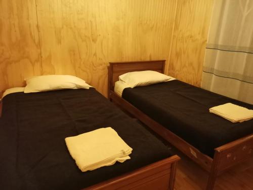 2 camas en una habitación con sábanas negras y toallas blancas en Cabañas Candelaria, en Los Ángeles