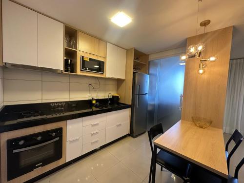 a kitchen with white cabinets and a wooden table at Apartamento Luxo St Bueno in Goiânia