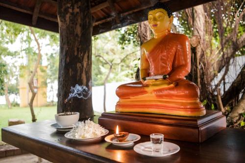 een standbeeld van een Boeddha zittend op een tafel met kaarsen bij Thaulle Pure Ayurveda Resort - Yala in Tissamaharama