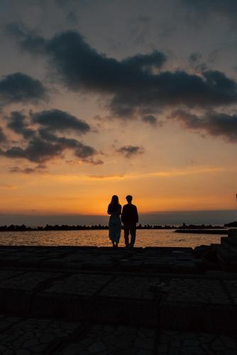 a man and a woman standing in front of a sunset at Atarayo Nishiizu Onsen in Izu