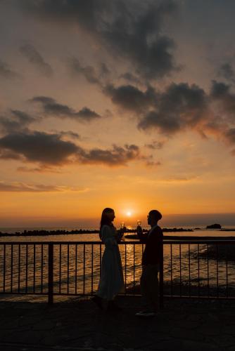 a man and woman standing in front of a sunset at Atarayo Nishiizu Onsen in Izu