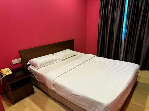 a bed in a bedroom with a pink wall at GOA INN HOTEL SDN BHD in Gua Musang