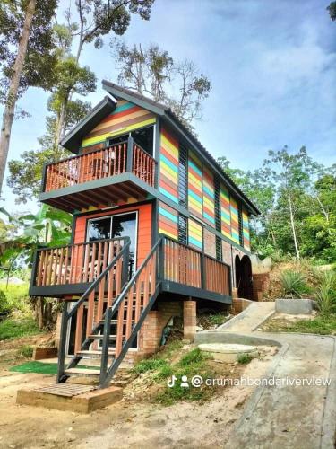 ein farbenfrohes Haus mit Balkon an der Seite in der Unterkunft CHALET COBEK D' RUMAH BONDA RIVER VIEW in Kampong Senawar