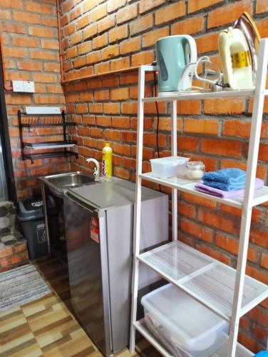 eine Küche mit Spüle und Ziegelwand in der Unterkunft CHALET COBEK D' RUMAH BONDA RIVER VIEW in Kampong Senawar