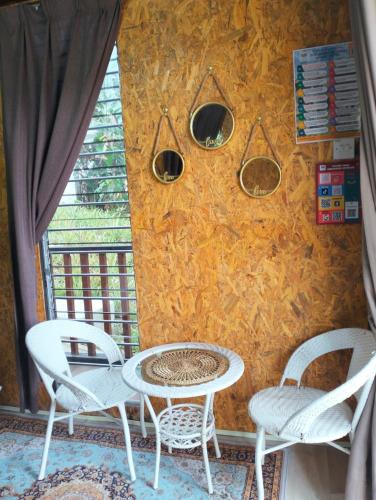 zwei Stühle und ein Tisch vor einer Wand in der Unterkunft CHALET COBEK D' RUMAH BONDA RIVER VIEW in Kampong Senawar