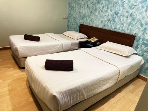 two beds in a hotel room with white sheets at GOA INN HOTEL SDN BHD in Gua Musang