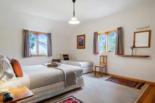 1 dormitorio con cama, mesa y ventanas en Herons Rise Vineyard Accommodation, en Kettering