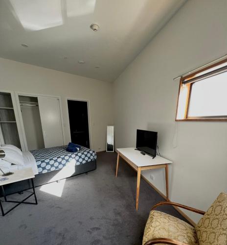 a bedroom with a bed and a desk with a laptop at On Top Backpackers in Dunedin