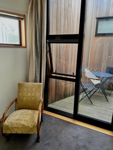 a room with a chair and a table and a window at On Top Backpackers in Dunedin