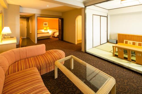 Mikawawan Resort Linx في Nishio: غرفة في الفندق مع أريكة وغرفة نوم