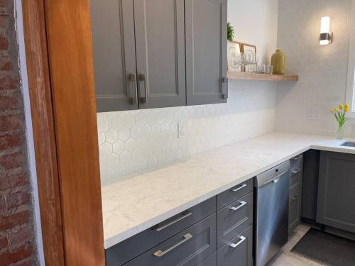uma cozinha com armários cinzentos e um balcão branco em BEAUTIFUL 3 BDRM HERITAGE HOME-MINS TO DOWNTOWN em Hamilton