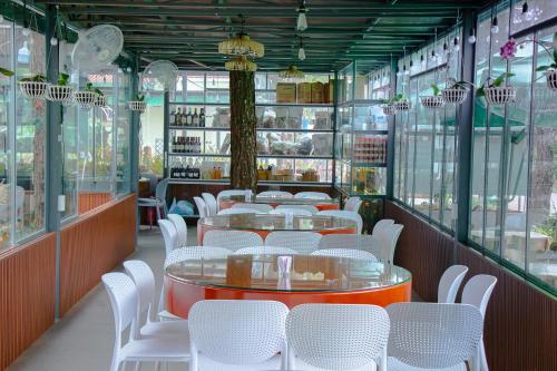 un restaurant avec des tables blanches et des chaises blanches dans l'établissement Mang Den Green Hotel, à Kon Tum