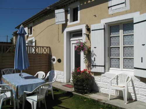a house with a table and chairs and an umbrella at La Vendange Family Gites in Gibourne