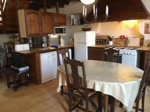 a kitchen with a table and chairs and a kitchen with white appliances at La Vendange Family Gites in Gibourne