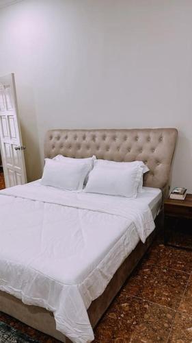 Kamilia Homestay KB City Centre في كوتا بْهارو: غرفة نوم بسرير كبير عليها شراشف ووسائد بيضاء
