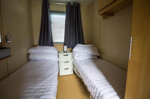 two beds in a small room with a window at Lovely 8 Berth Caravan At Naze Marine Holiday Park Ref 17012p in Walton-on-the-Naze