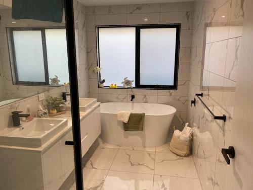 a white bathroom with a tub and a sink at Sanary a modern beach home in Martha Cove ideally located for the Harry Potter Hidden forest experience in Safety Beach