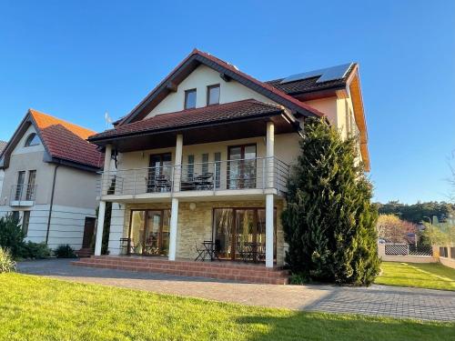 a large house with a balcony on a lawn at Willa Mare in Dębki