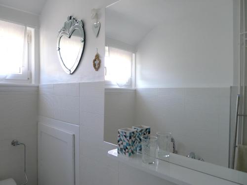 Baño blanco con espejo y lavabo en Un gîte dans la vallée, en Obersteinbach