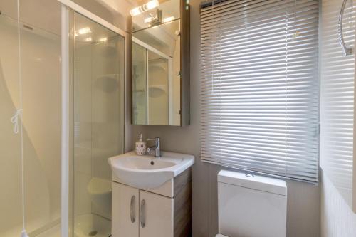 a white bathroom with a sink and a shower at Beautiful 6 Berth Caravan By The Beach In Suffolk Ref 40076nd in Lowestoft