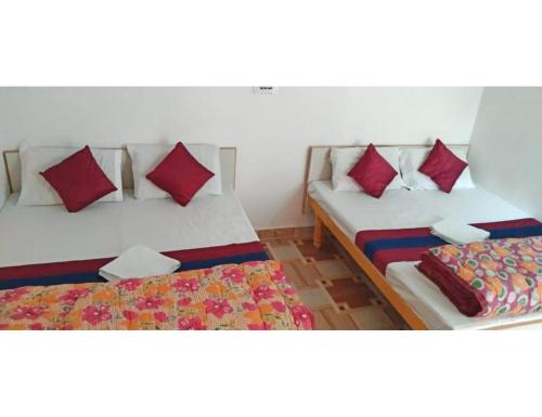 2 bedden in een kamer met rode kussens bij Hotel Amandeep Galaxy, Barkot in Barkot