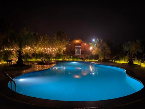una piscina por la noche con una casa en el fondo en LA'S FARMSTAY en Tây Ninh
