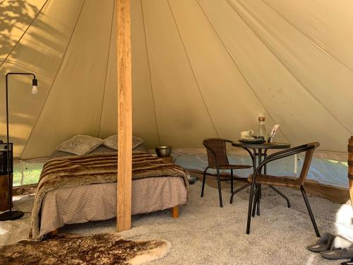 a bedroom with a bed and a table in a tent at Karula Stay - Exclusive Glamping Experience with Private Sauna in Ähijärve