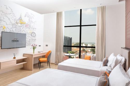 a hotel room with two beds and a desk at Capri by Fraser, Phnom Penh in Phnom Penh