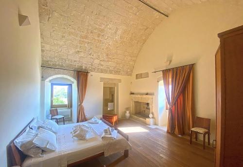 a bedroom with a white bed and a room with a fireplace at Masseria La Millenaria in San Foca