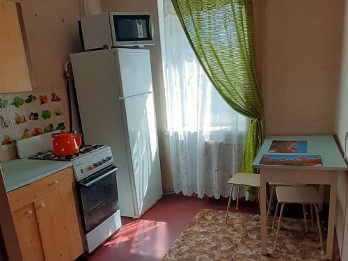 eine Küche mit einem Kühlschrank und einem Tisch mit einer Mikrowelle in der Unterkunft Эконом вариант - спальный район in Tschernihiw
