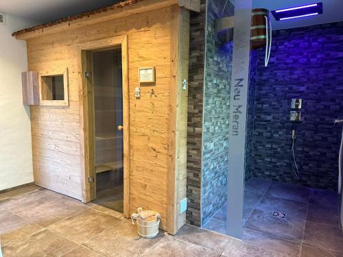 eine Dusche in einem Zimmer mit einer Holzwand in der Unterkunft Hotel Restaurant Neu Meran in Bad Reichenhall