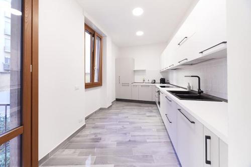 a white kitchen with white counters and a sink at Elegant Apartment in Milan